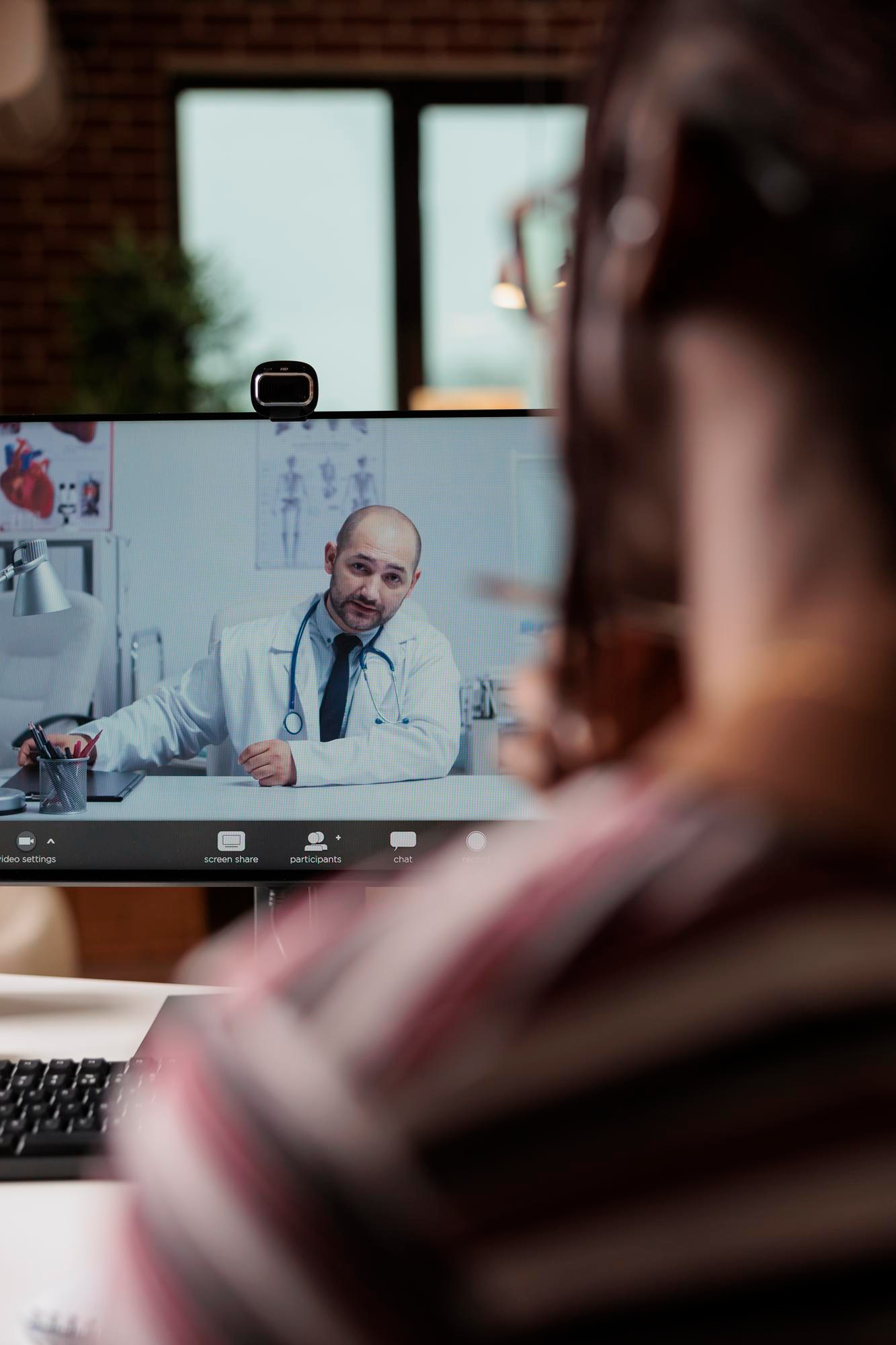 Paciente olhando tela de computador com médico em chamada